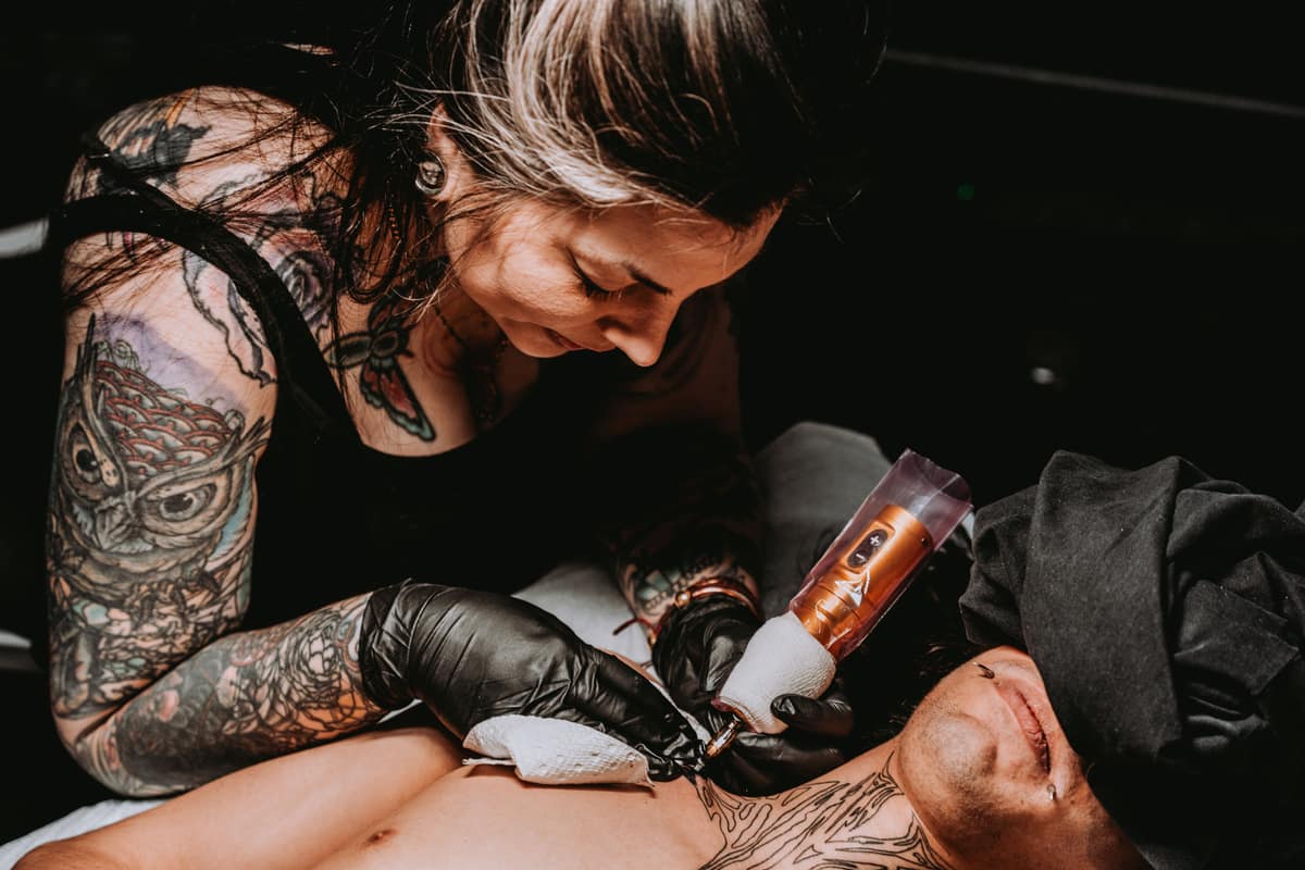 A tattoo artist working on a chest piece in the building