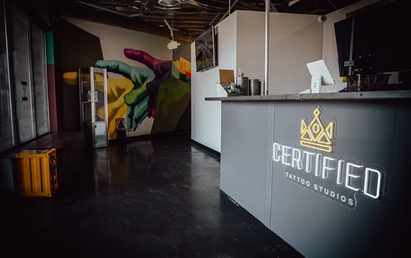The front desk and lobby at 3725 Drennan Road, Colorado Springs, with the Certified Tattoo Studios neon sign