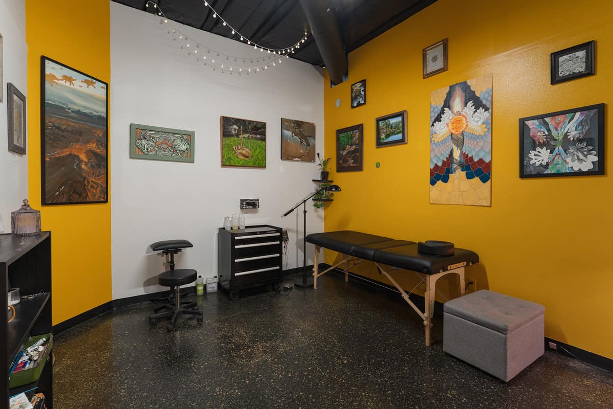A suite with gold walls, framed art, a tattoo bed and a tool chest